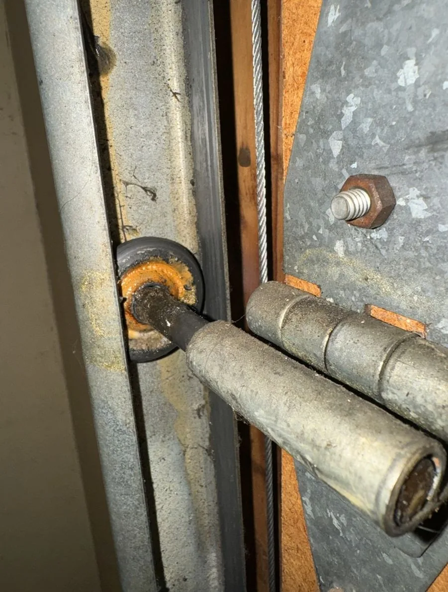 Close-up of a garage door lift cable and bottom bracket