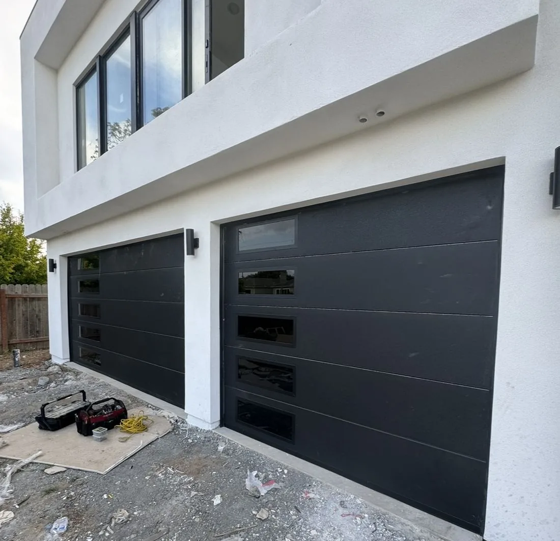 Two new black modern garage doors installed on a new-construction home