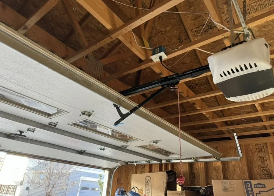 Ceiling-mounted garage door opener and rail in an open-beam garage