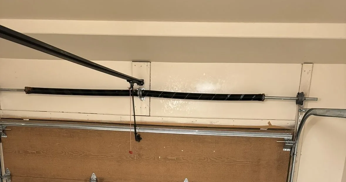 Torsion spring mounted on its shaft above a garage door